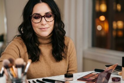 Femme portant des lunettes en acétate écaille avec un maquillage smoky bordeaux et un pull col roulé camel, tendances automne-hiver 2026